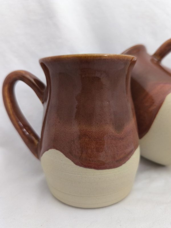Handmade ceramic coffee mug with a rich, warm brown glaze and natural raw clay on the bottom, featuring unique drips of glossy brown glaze