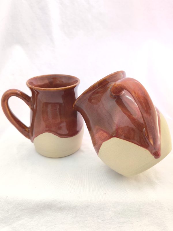 Handmade ceramic coffee mug with a rich, warm brown glaze and natural raw clay on the bottom, featuring unique drips of glossy brown glaze