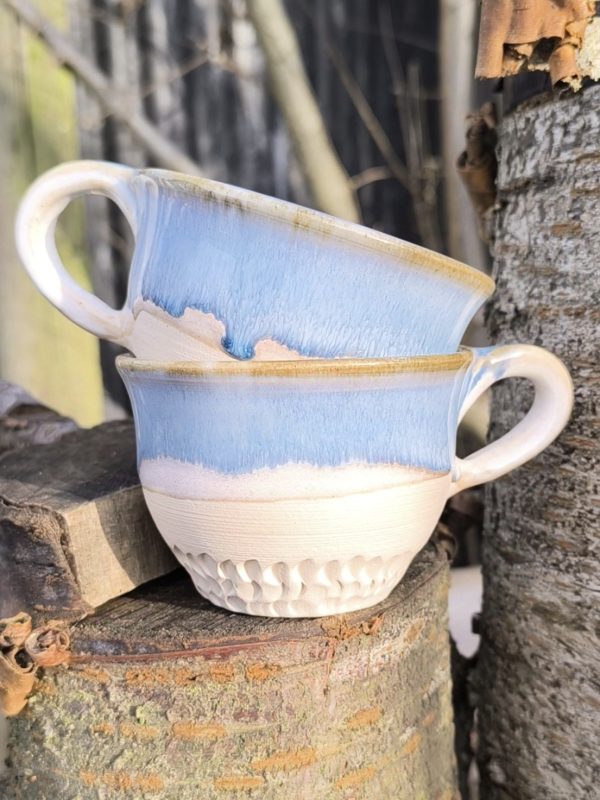 Handmade ceramic tea cup with light blue and white glaze, raw clay textured base, and comfortable handle, perfect for tea, coffee, or lattes
