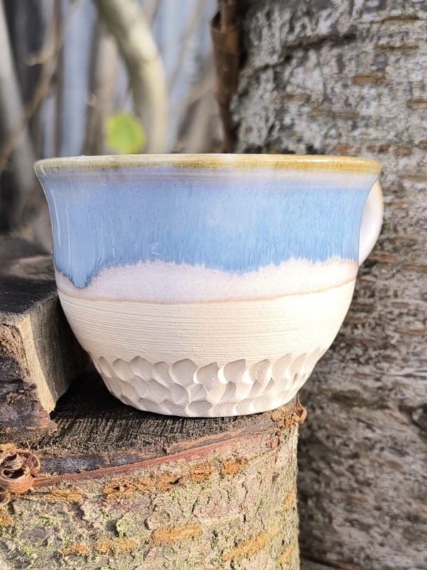Handmade ceramic tea cup with light blue and white glaze, raw clay textured base, and comfortable handle, perfect for tea, coffee, or lattes
